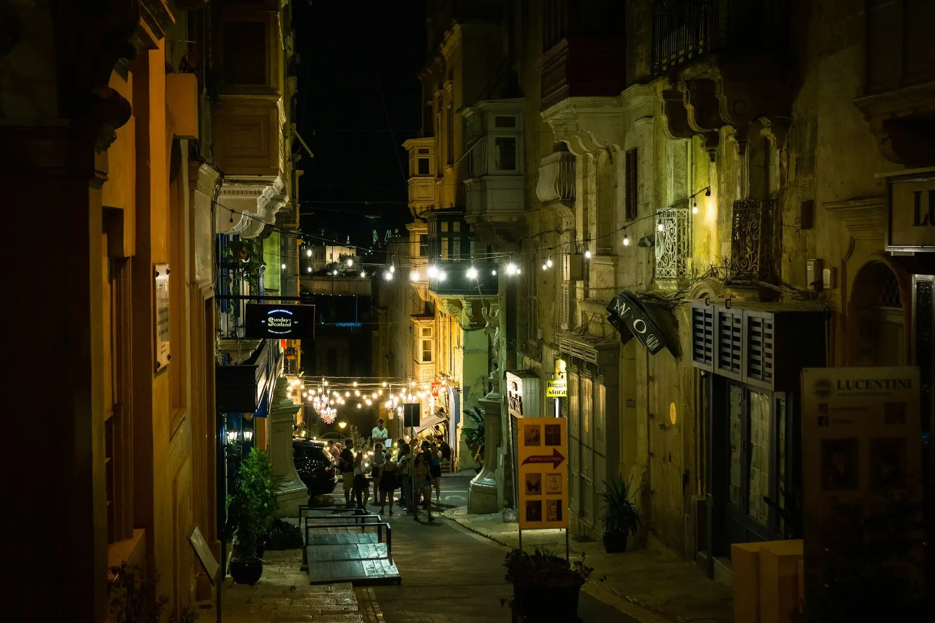 Beleuchtete Gasse am Abend mit Balkonen und Laternen
