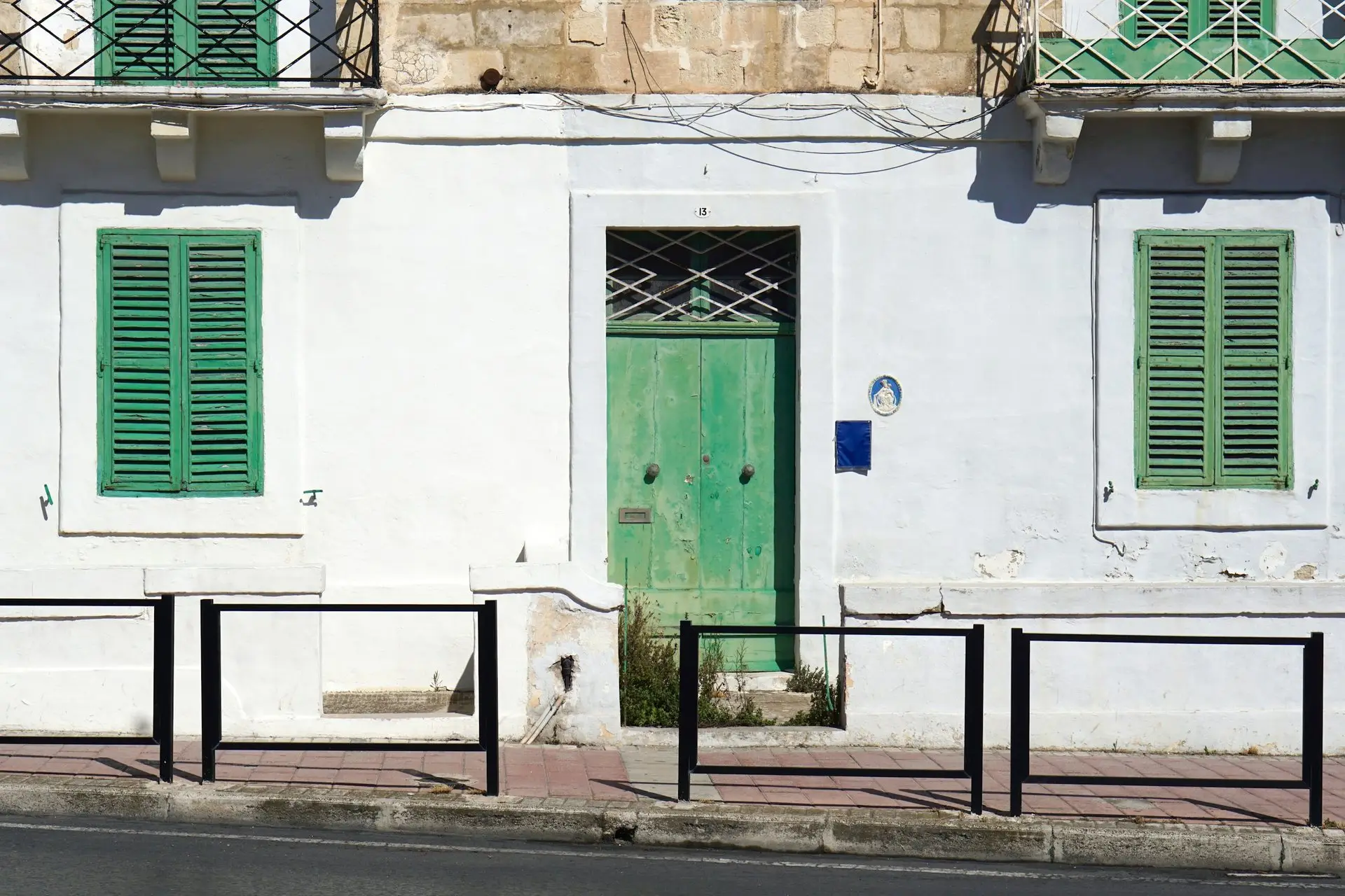 Grüne Haustür zwischen grünen Fensterläden an heller Wand