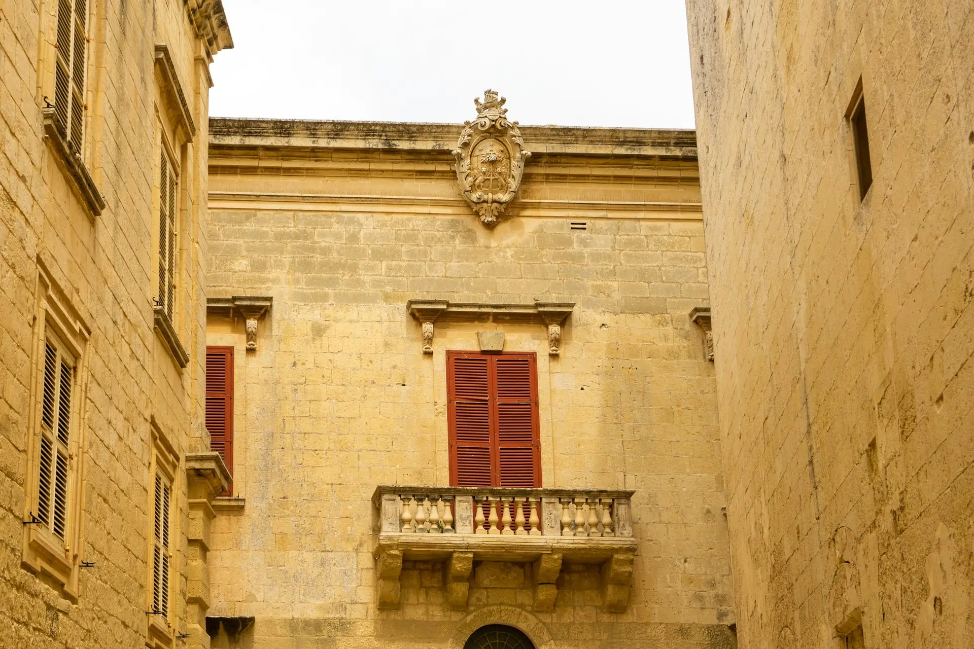Kalksteinhaus mit Balkon und roten Fensterläden