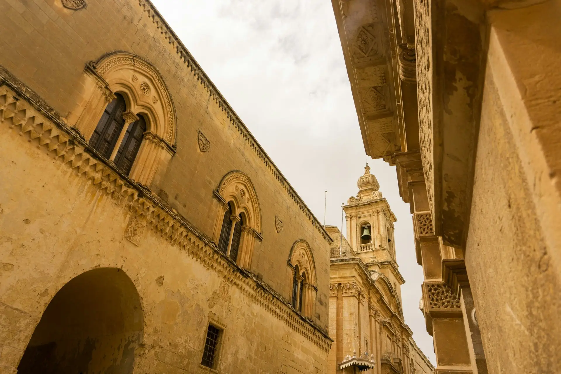 Warme Kalksteingasse in Mdina mit einem Turm dahinter