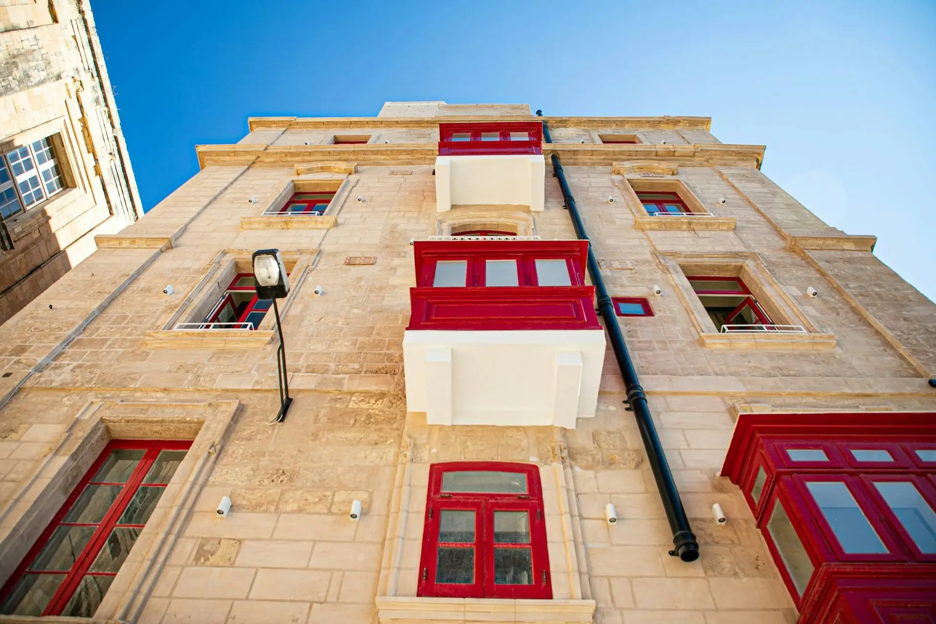 Fassade mit roten Holzbalkonen, von unten gesehen