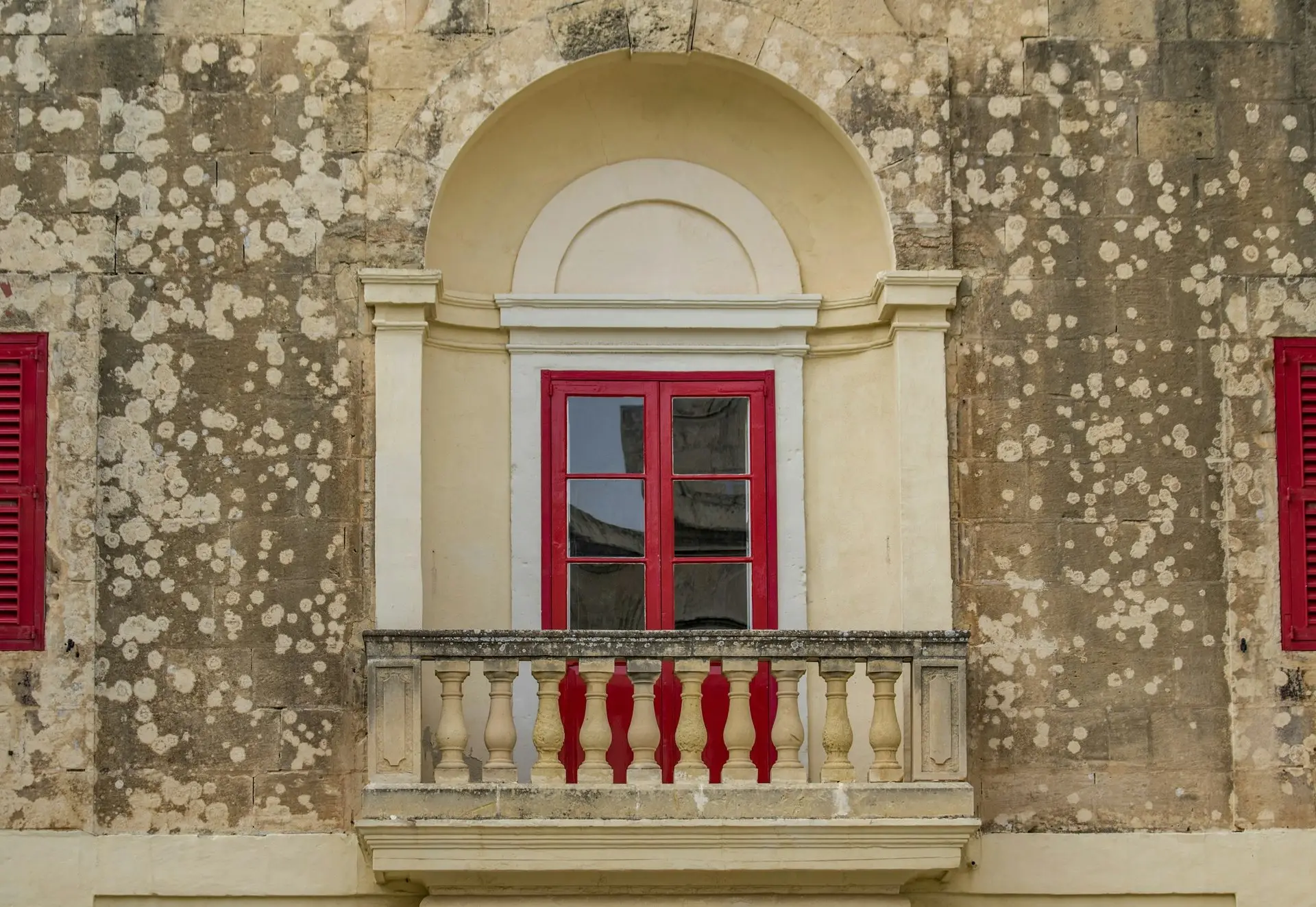 Fenster mit roten Holzläden in heller Kalksteinwand
