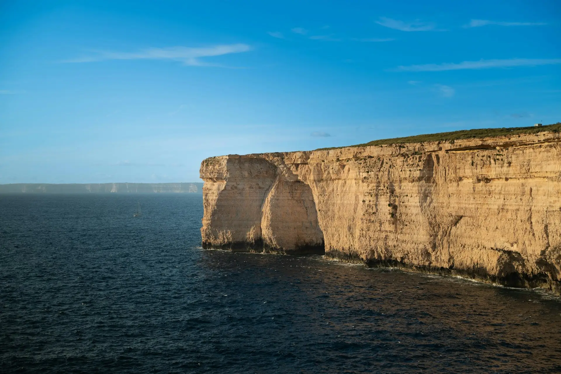 Hohe Kalksteinwand fällt ins tiefblaue Meer