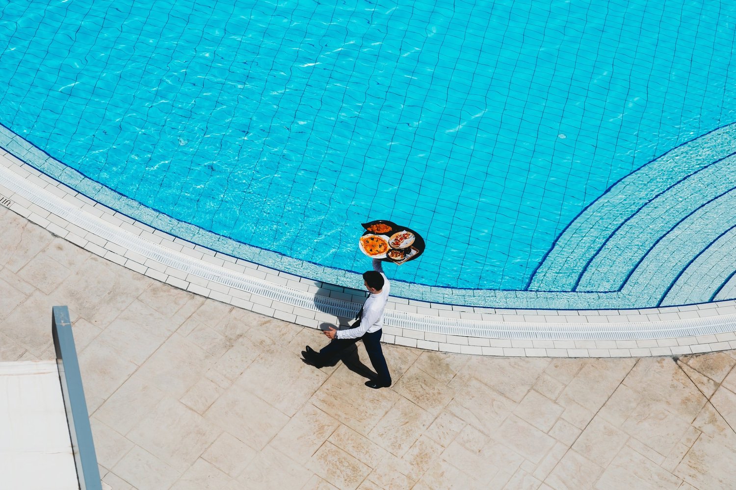 Kellner mit Tablett am Pool eines Hotels