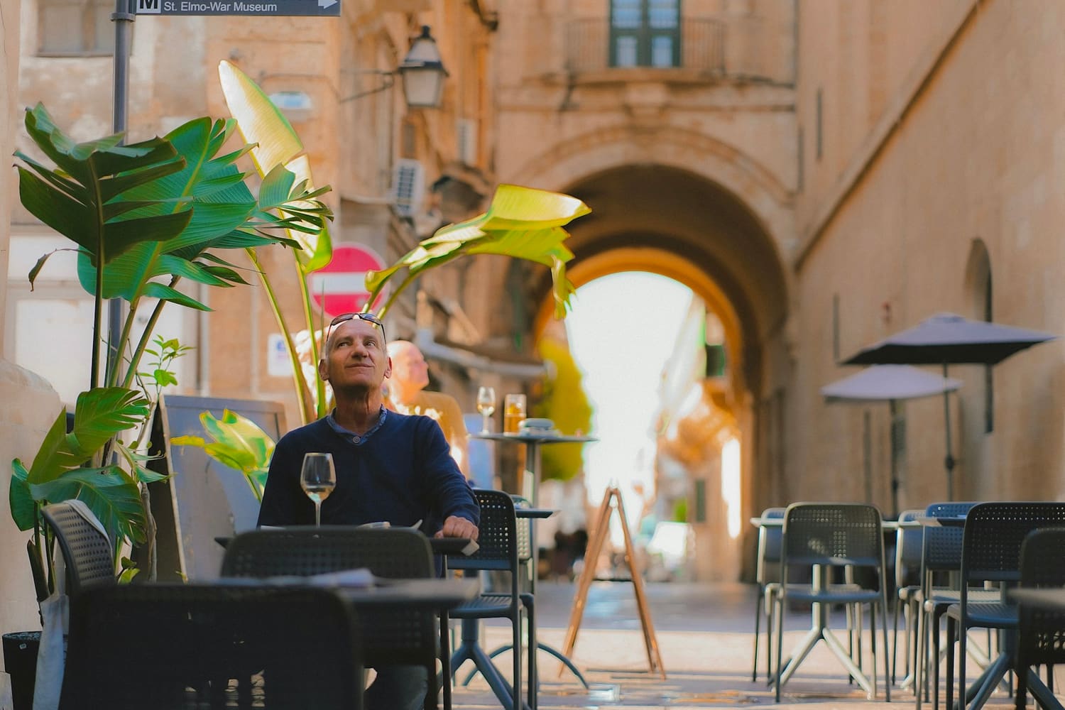 Mann an einem Cafétisch in einer Altstadtgasse von Valletta